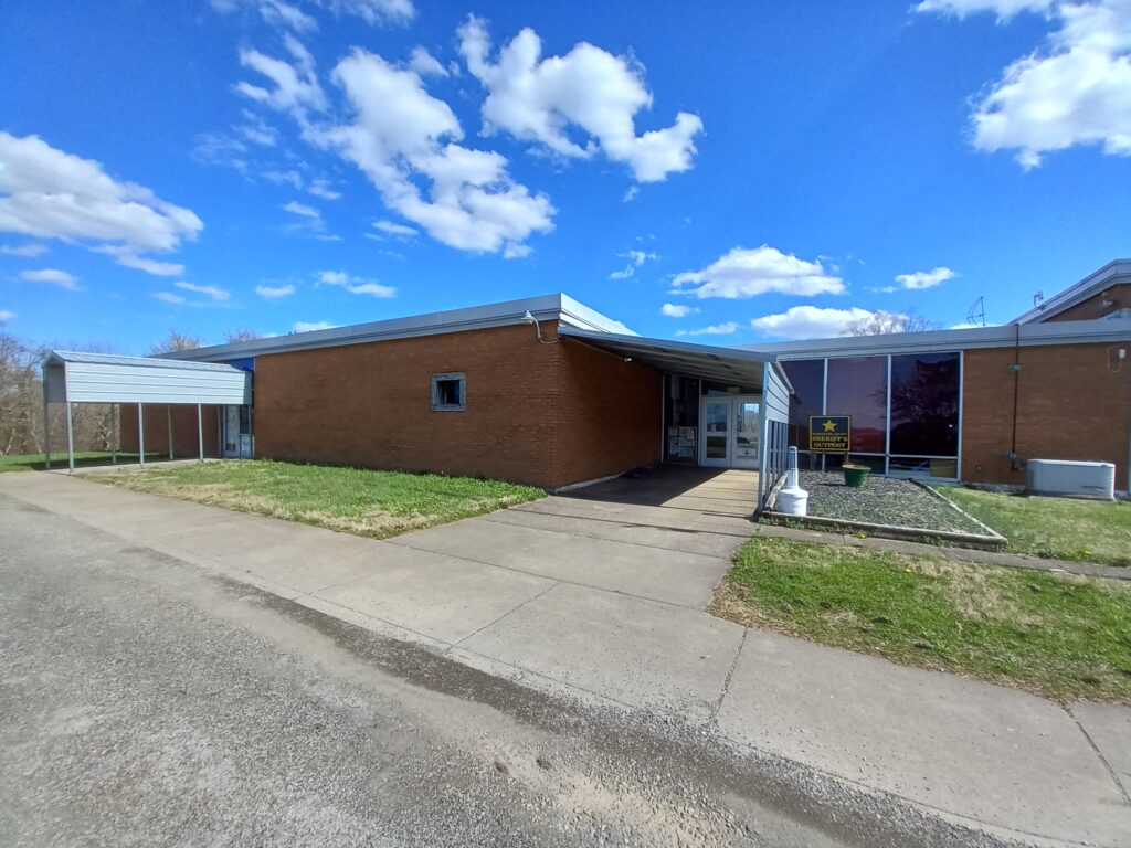 picture of the front of the building which is orange brick with blue metal awnings